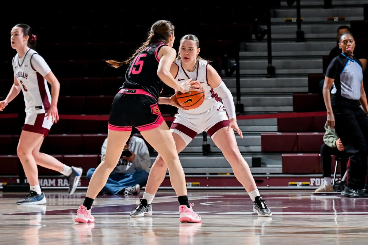 A Fordham basketball player locks down an opposing attacker from the George Mason University. 