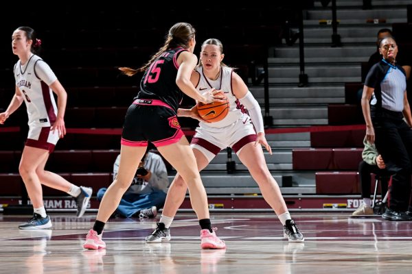 A Fordham basketball player locks down an opposing attacker from the George Mason University. 