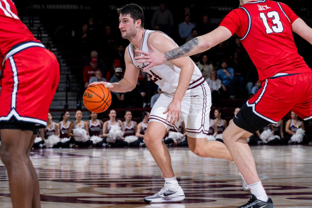 Matt Zona dribbles the ball, surrounded by defending Dayton Flyers (Courtesy of Fordham Athletics).