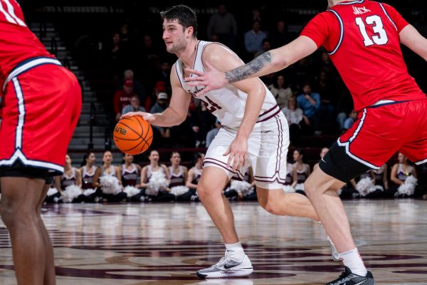 Matt Zona dribbles the ball, surrounded by defending Dayton Flyers (Courtesy of Fordham Athletics).