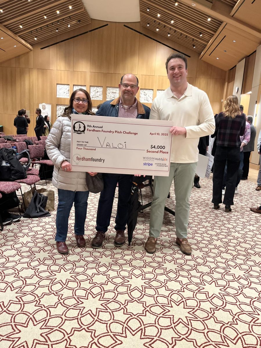 Tristan Nevotne holds up his second place prize money with Fordham Football Gridiron President Dominic Curcio and his wife. (Tristan Nevotne for The Fordham Ram)