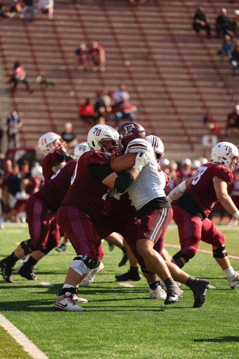 Members of the Fordham football team lift the Ram-Crusader Cup after defeating Holy Cross.