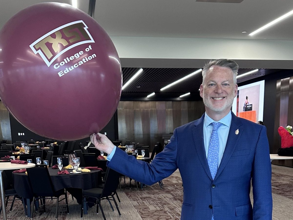 Michel P. O’Malley holding a “Texas State University, College of Education” balloon.